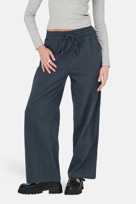 Pantalon bleu d'ONLY, à jambes larges et avec un cordon de serrage à la taille, porté avec un t-shirt gris.