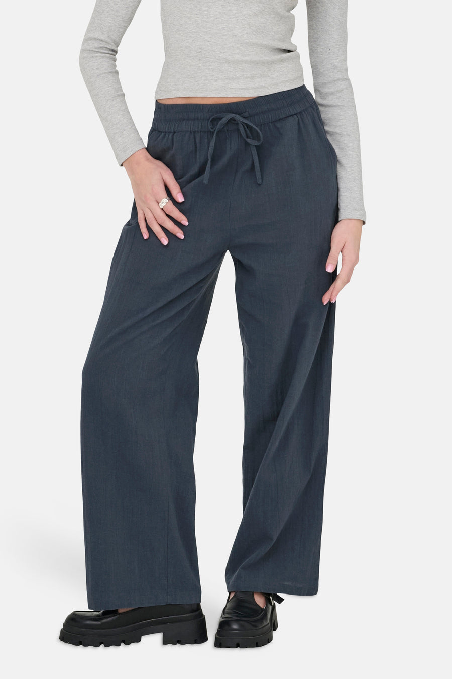 Pantalon bleu d'ONLY, à jambes larges et avec un cordon de serrage à la taille, porté avec un t-shirt gris.