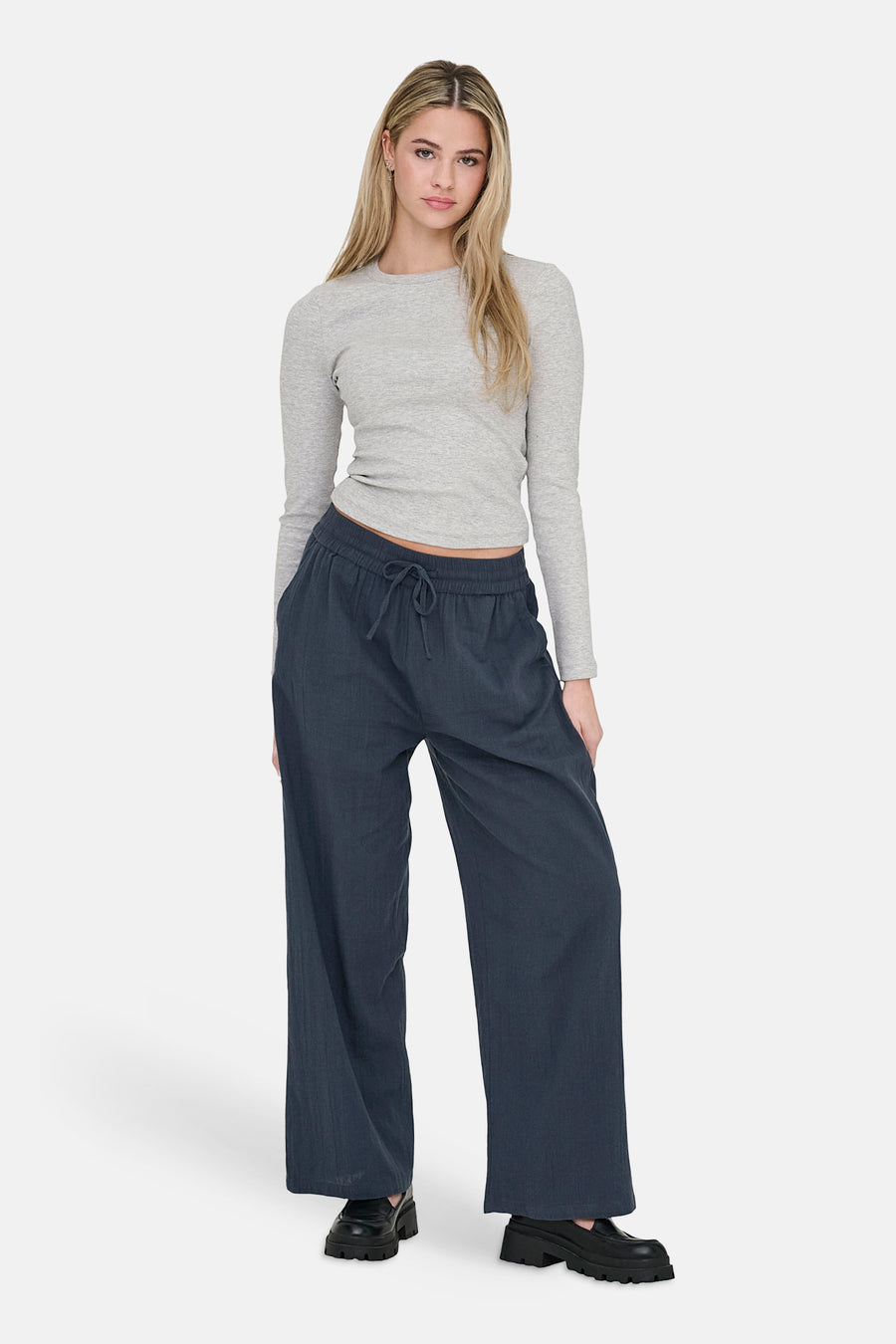Blauwe broek van ONLY, met wijde pijpen en een trekkoord in de taille, gedragen met een grijs shirt.
