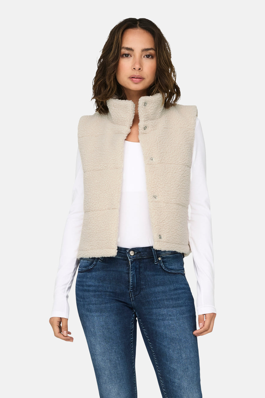 Ecru bodywarmer van ONLY®, met knoopsluiting, gedragen over een wit shirt en donkerblauwe jeans.
