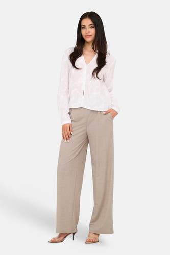Beige broek van JDY met wijde pijpen, gedragen door een model met een witte geborduurde blouse en transparante hakken.