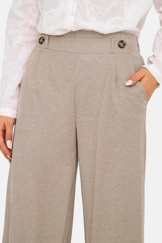 Beige broek van JDY met knopen, plooien en steekzakken, gedragen met een witte geborduurde blouse.
