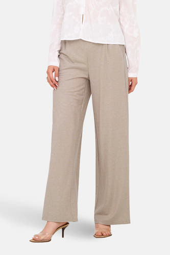 Beige broek van JDY, met wijde pijpen en gedragen met transparante hakken en een witte blouse.