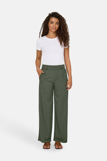 Kaki broek van JDY, met wijde pijpen, knoopdetails en een witte top.
