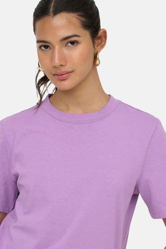 T-shirt violet à manches courtes avec col rond de ONLY®, porté par un mannequin avec des boucles d'oreilles dorées.