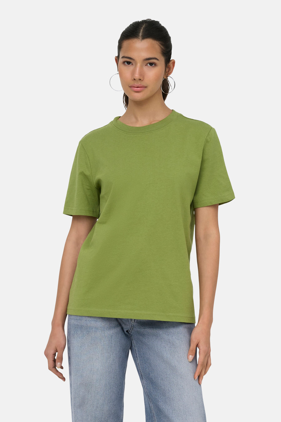 T-shirt vert de ONLY® à col rond, porté par un mannequin avec un jean clair et des boucles d'oreilles argentées.