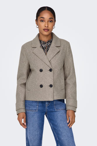 Beige korte jas van ONLY, met dubbele rij knopen en gedragen met een blouse met print en blauwe jeans.
