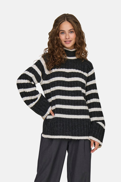 Sweat-shirt gris à col rond de JDY, avec des rayures noires et blanches. Porté avec un pantalon foncé et des baskets noires.