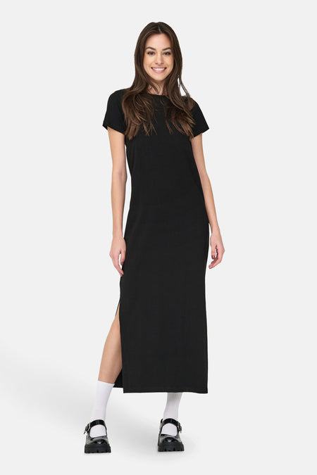 Robe noire à manches courtes de JDY, avec une haute fente et associée à des chaussettes blanches et des chaussures noires.