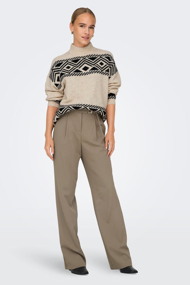 Ecru rolkraagtrui van ONLY, met zwart geometrisch patroon op de borst en gedragen met een bruine pantalon.
