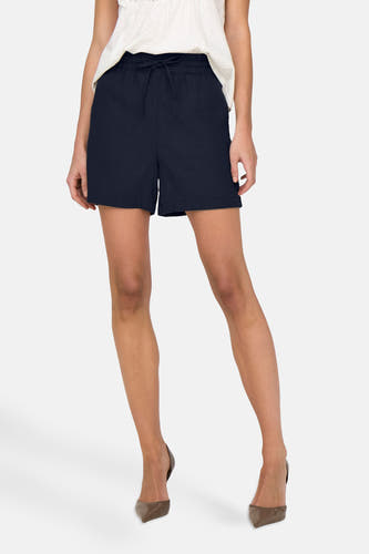 Donkerblauwe short van JDY, met een elastische tailleband en vetersluiting, gedragen met taupekleurige hakken.
