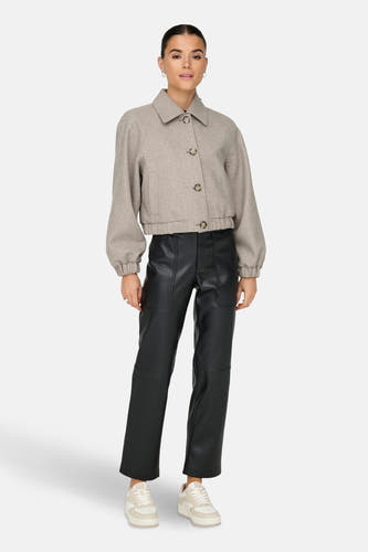 Manteau court beige ONLY, avec des manches longues et une fermeture à boutons, porté avec un pantalon noir et des baskets blanches.
