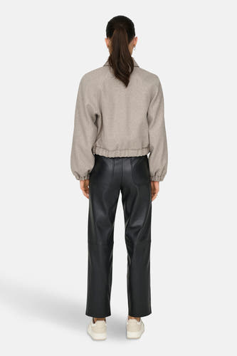 Veste courte beige de ONLY®, avec des manches longues, associée à un pantalon noir et des baskets crème, vue arrière.