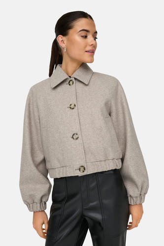Manteau court beige ONLY, avec des manches longues et une fermeture à boutons, associé à un pantalon en cuir noir.