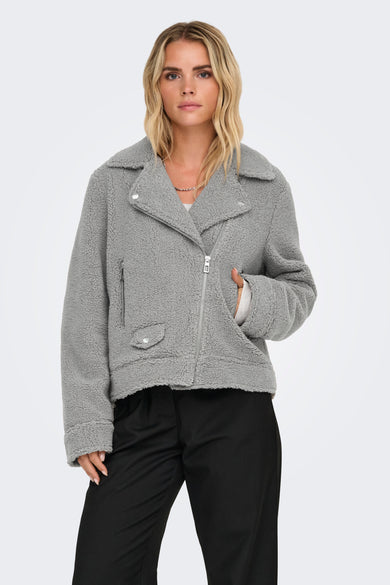 Manteau gris court d'ONLY, avec une douce texture et une fermeture éclair argentée, porté avec un pantalon noir.