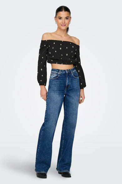 Blouse noire à longues manches ONLY, avec encolure dégagée et motifs blancs en forme de losange.