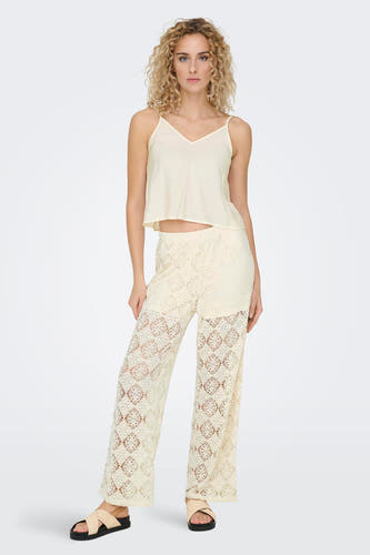 Ecru mouwloze blouse van ONLY, gedragen met kanten broek en sandalen met bandjes.