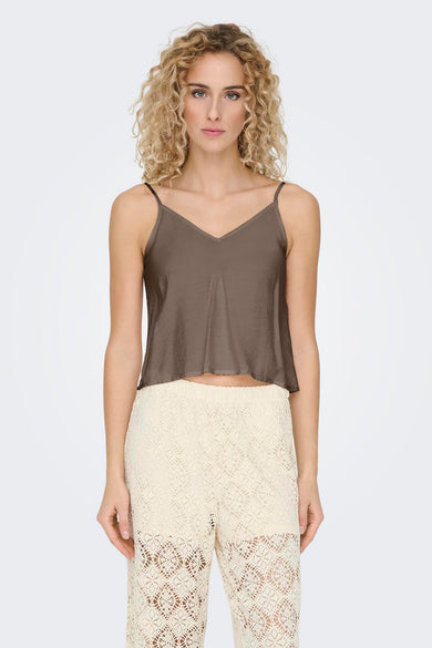 Mouwloze bruine blouse van ONLY, gedragen met gebreide, crèmekleurige broek.
