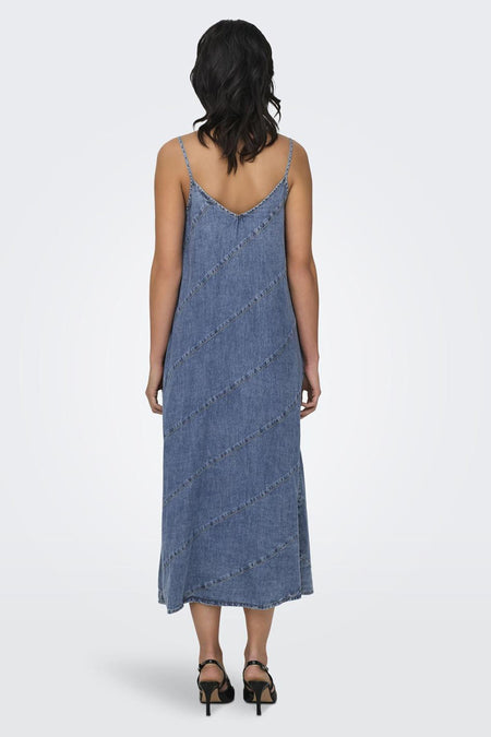 Middenblauw mouwloos denim jurkje van ONLY® met diagonale naden, achterkant, gedragen met zwarte sandalen.