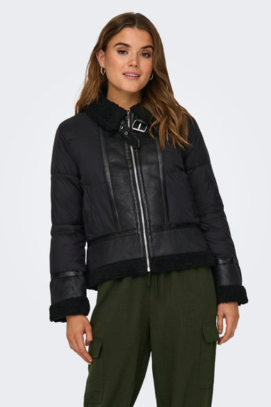 Zwarte korte jas van ONLY, met faux lederen details en een rits vooraan, gedragen met een groene broek.
