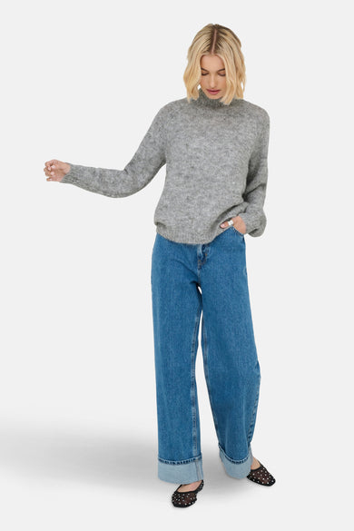 Grijze coltrui van JDY, gedragen met wijde jeans met omgeslagen pijpen en zwarte, doorzichtige ballerina's met stippen.
