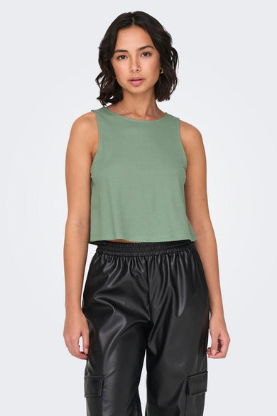 Groene top van ONLY®, gecombineerd met zwarte leren broek en gouden oorbellen.