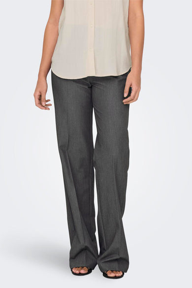 Pantalon gris de ONLY, avec des jambes larges et porté avec une blouse beige et des sandales.