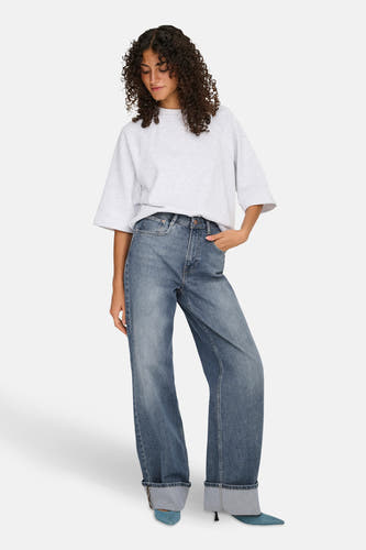 Mid blue denim wijde jeans van HOPE, gecombineerd met een grijze top en blauwe hakken.
