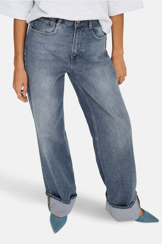 Wijdvallende mid-blue denim jeans van ONLY, met opgerolde pijpen en gecombineerd met blauwe pumps.
