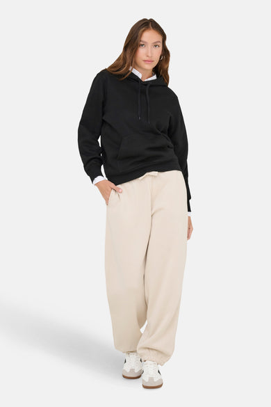 Zwarte sweater met kap van ONLY, gestyled met beige joggingbroek en witte sneakers.
