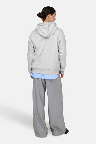 Grijze sweater met kap van ONLY, met lange wijde grijze broek en blauw overhemd.