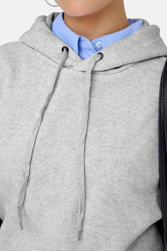 Grijze sweater met kap van ONLY, met trekkoorden en een lichtblauwe blouse onder de sweater.
