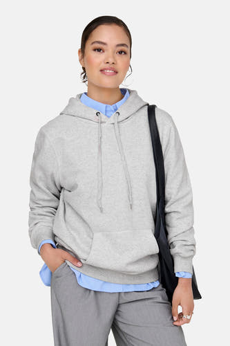 Grijze sweater met kap van ONLY, gedragen over een blauw overhemd met grijze broek en zwarte tas.
