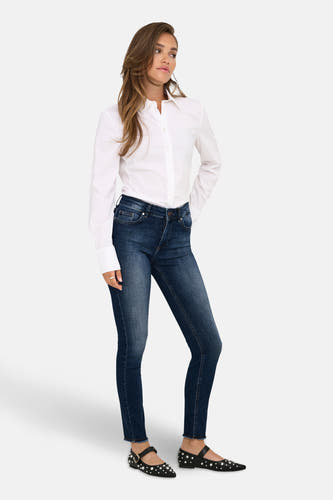 Skinny jeans in donkerblauwe denim van ONLY, met zichtbare stiksels en gedragen met een wit overhemd en zwarte ballerina's.
