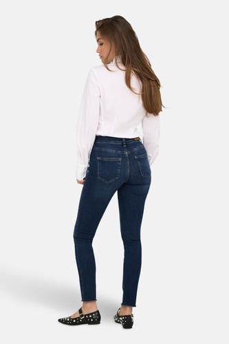Skinny jeans van donkerblauw denim van ONLY, gedragen met een wit overhemd en zwarte, bezaaide ballerina's.
