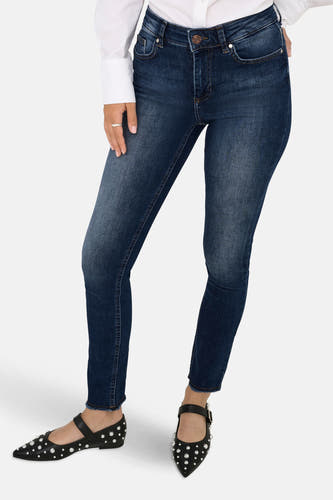Skinny jeans van donkerblauw denim van ONLY®, gecombineerd met een wit overhemd en zwarte schoenen met noppen.
