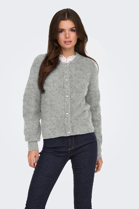 Grijs vest van JDY met lange mouwen en knoopsluiting, gedragen met een wit kanten kraagdetail en een donkere jeans.
