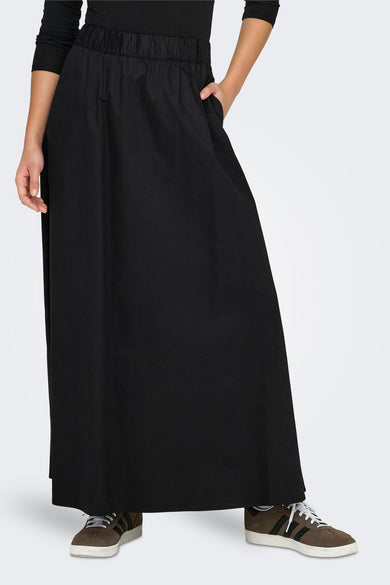 Lange zwarte rok van ONLY, met elastische tailleband en steekzak, gecombineerd met bruine sneakers.
