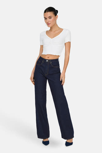 Jean bleu marine large d'ONLY, avec un bord jaune et porté avec un haut court blanc.