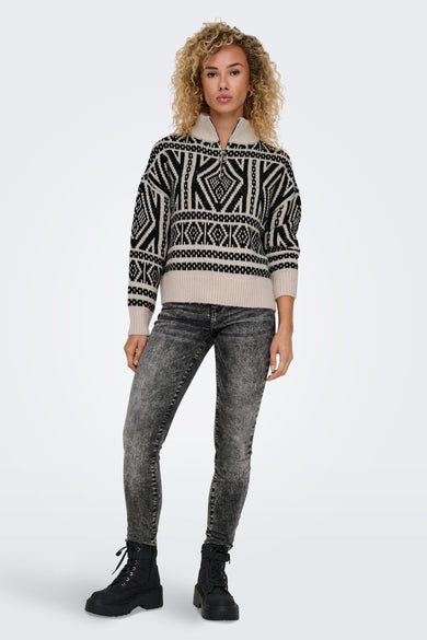 Ecru rolkraag trui van ONLY, met een zwart geometrisch patroon en grijze jeans en zwarte laarzen.
