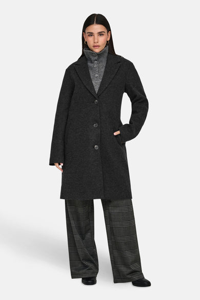Manteau long noir de JDY, à boutons, porté sur une veste grise et un pantalon large rayé.