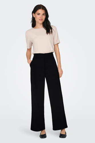 Pantalon noir de JDY, associé à un haut beige et des ballerinas noires.