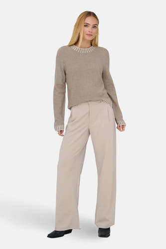 Ecru broek van JDY, gecombineerd met een beige trui met streepdetails, en zwarte schoenen.

