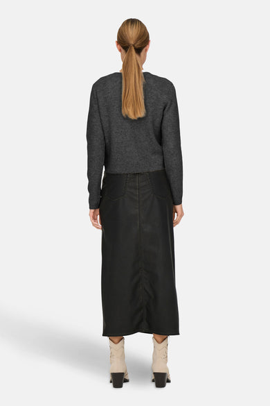Gilet gris de JDY, avec des manches longues et porté avec une longue jupe noire et des bottes.