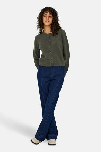 Kaki cardigan van JDY, met lange mouwen en knoopsluiting, gecombineerd met donkerblauwe jeans en crèmekleurige schoenen.
