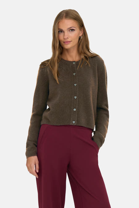 Bruin vest van JDY, met lange mouwen en knoopsluiting, gecombineerd met een bordeauxrode broek.
