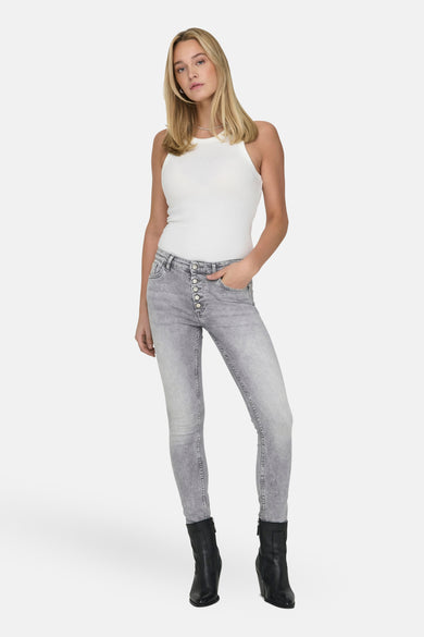 T-shirt écru d'ONLY, porté avec des jeans gris à fermeture éclair et des bottes noires.