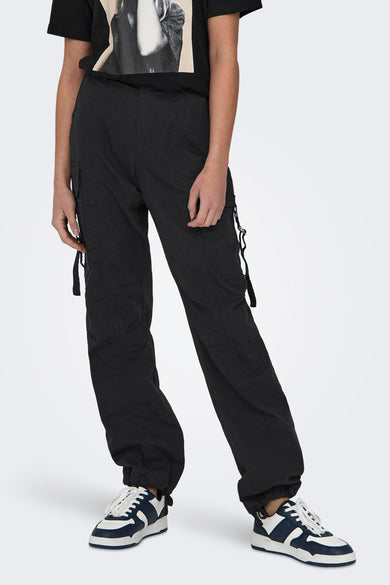 Pantalon cargo gris ONLY, avec poches et bandes, porté avec un T-shirt noir et des baskets bleu et blanc.