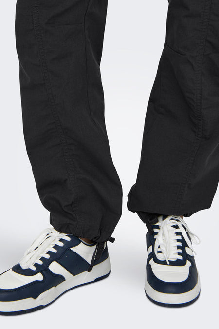 Jean cargo gris ONLY, avec des lacets aux chevilles et associé à des baskets blanches et bleu foncé.