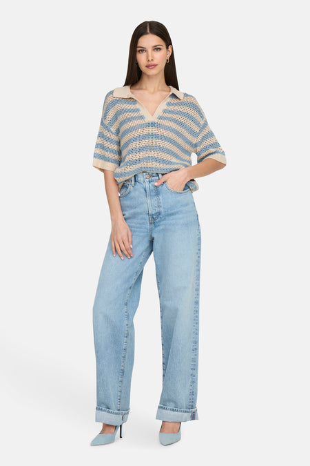 Blauwgebreide polo met korte mouwen van JDY, met beige strepen gecombineerd met wijde jeans en blauwe pumps.
